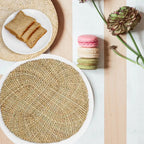 Round placemat hand woven in a tight spiral of natural straw