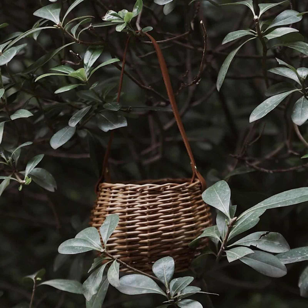 Round woven rattan planter basket with a brown leather look strap