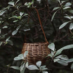 Round woven rattan planter basket with a brown leather look strap