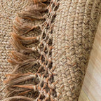 Round jute rug with a tassel fringe in a bright room