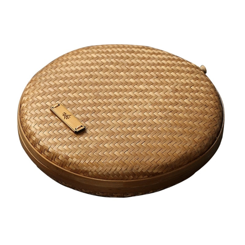 Two flat round rattan boxes with fitted lids on a table runner