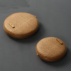 Two flat round rattan boxes with fitted lids on a table runner