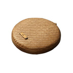 Two flat round rattan boxes with fitted lids on a table runner