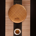 Two flat round rattan boxes with fitted lids on a table runner