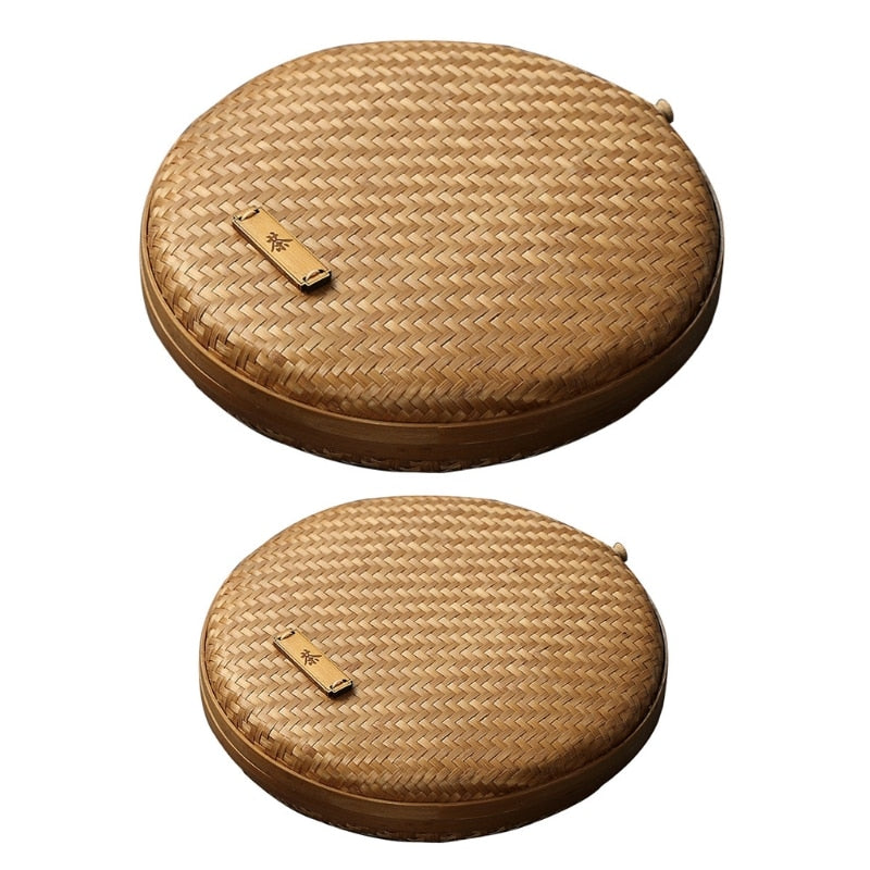 Two flat round rattan boxes with fitted lids on a table runner