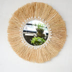 Round mirror framed by a natural fiber fringe