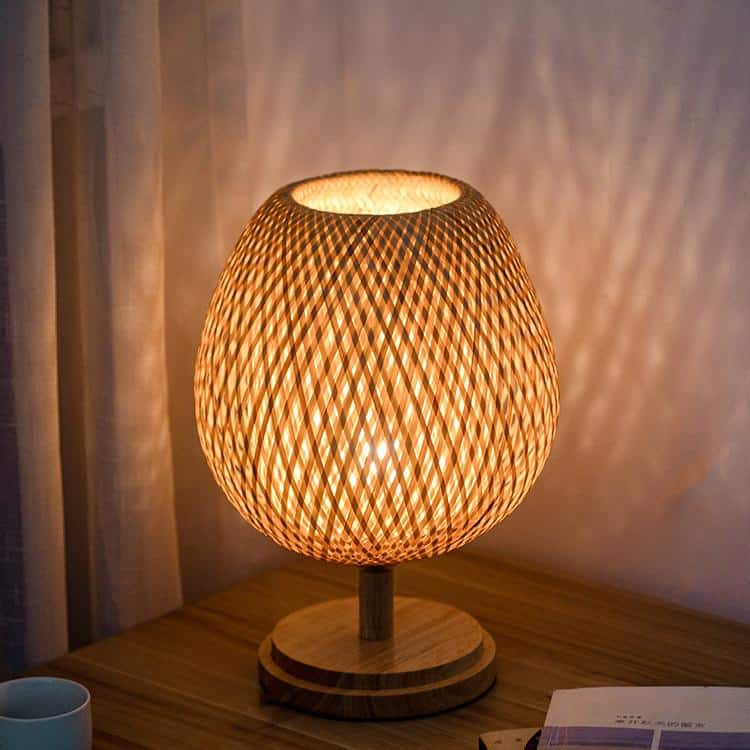Round bedside lamp with a hand woven rattan shade on a solid wood base
