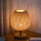 Round bedside lamp with a hand woven rattan shade on a solid wood base