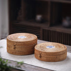 Round woven rattan box with a lid topped by a hand painted ceramic knob