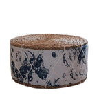 Round rattan pouf with green plant patterns woven on a white ground
