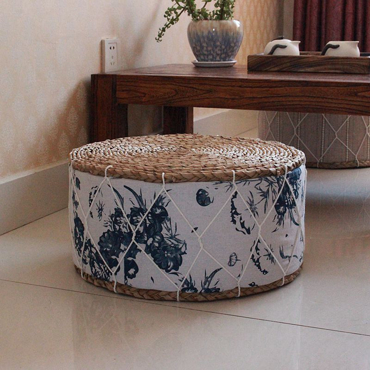 Round rattan pouf with green plant patterns woven on a white ground