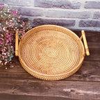 Round rattan serving tray with two light wooden handles