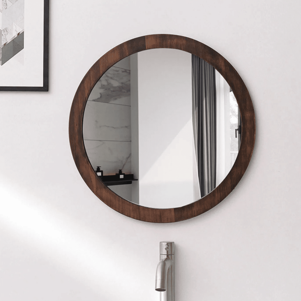 Round wall mirror with a dark wood frame above a sink