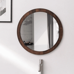 Round wall mirror with a dark wood frame above a sink