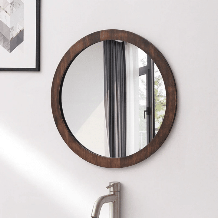 Round wall mirror with a dark wood frame above a sink