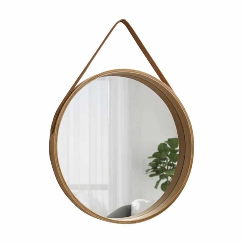 Round light wood mirror hanging from a brown strap