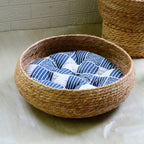 Large round low woven basket with a blue striped cushion