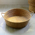 Large round low woven basket with a blue striped cushion