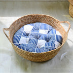 Large round low woven basket with a blue striped cushion