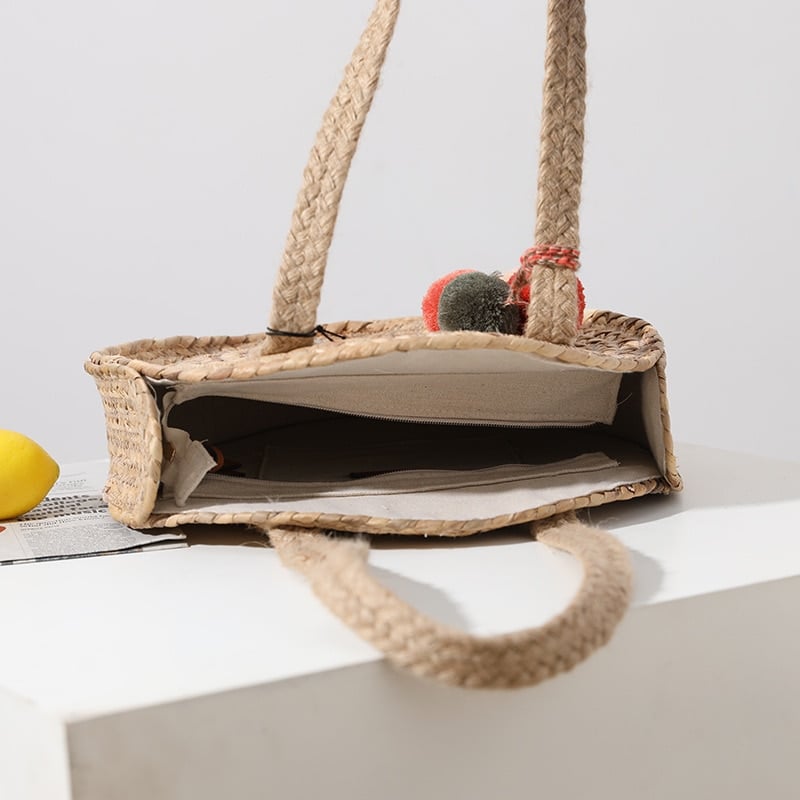 Round hand woven crossbody bag with a textured weave and hand knotted pompoms