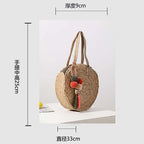 Round hand woven crossbody bag with a textured weave and hand knotted pompoms