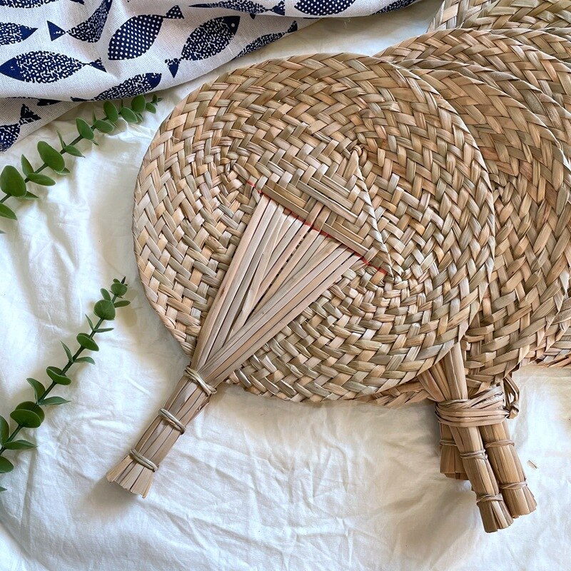 Round woven hand fan with a handle made of bundled tied stems
