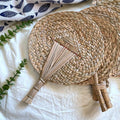 Round woven hand fan with a handle made of bundled tied stems