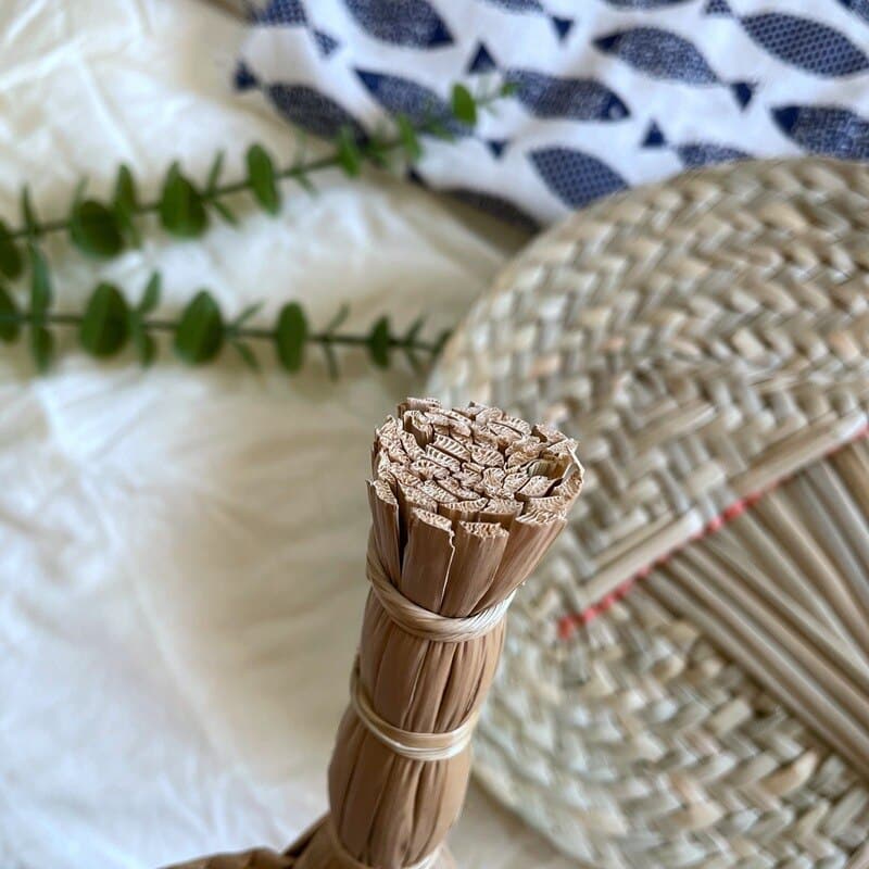 Round woven hand fan with a handle made of bundled tied stems