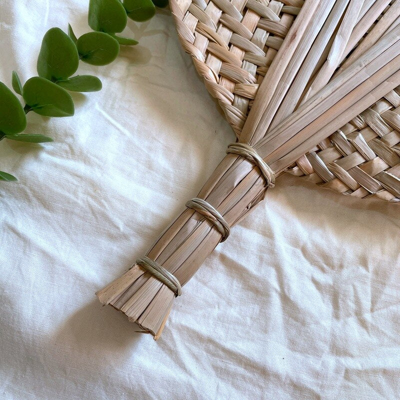 Round woven hand fan with a handle made of bundled tied stems