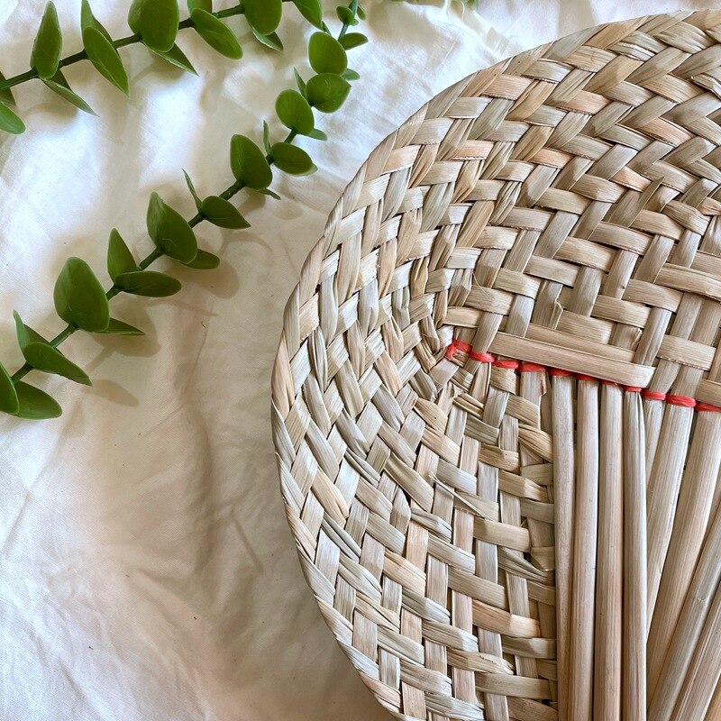 Round woven hand fan with a handle made of bundled tied stems