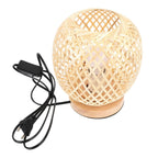 Round bedside lamp with a hand woven rattan shade on a woven base