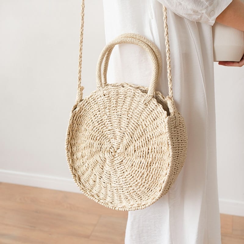 Round hand woven rattan crossbody bag with an adjustable strap in brown or beige