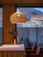 Round woven rattan globe pendant above a dining table