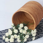 Round straight sided woven rattan bucket holding white flowers