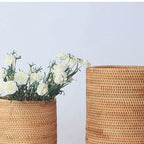 Round straight sided woven rattan bucket holding white flowers
