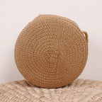 Round brown woven straw crossbody bag worn on the shoulder