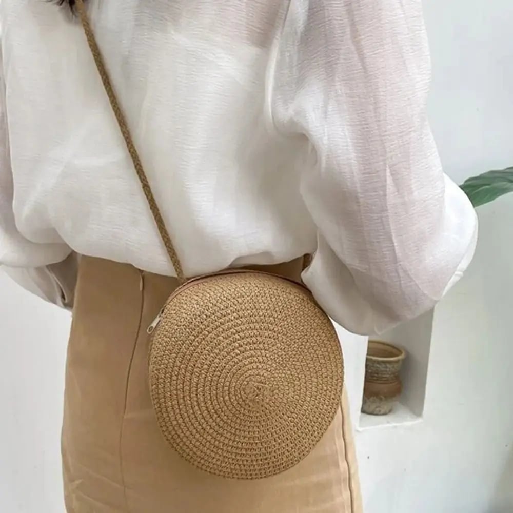 Round brown woven straw crossbody bag worn on the shoulder