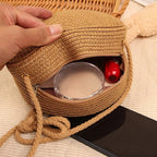 Round brown woven straw crossbody bag worn on the shoulder