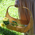 Boat shaped rattan flower basket with tall handle carrying sunflowers