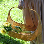 Boat shaped rattan flower basket with tall handle carrying sunflowers
