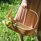 Boat shaped rattan flower basket with tall handle carrying sunflowers