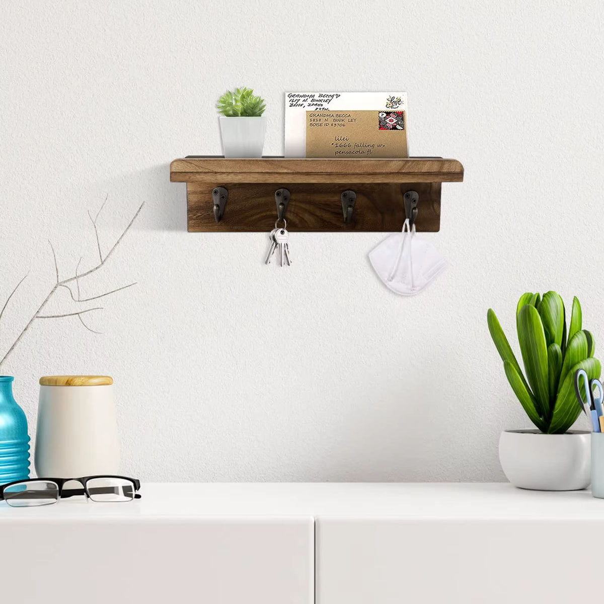 Rustic wood key holder shelf with four hooks holding keys and mail
