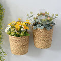 Two natural seagrass wall baskets holding flowers