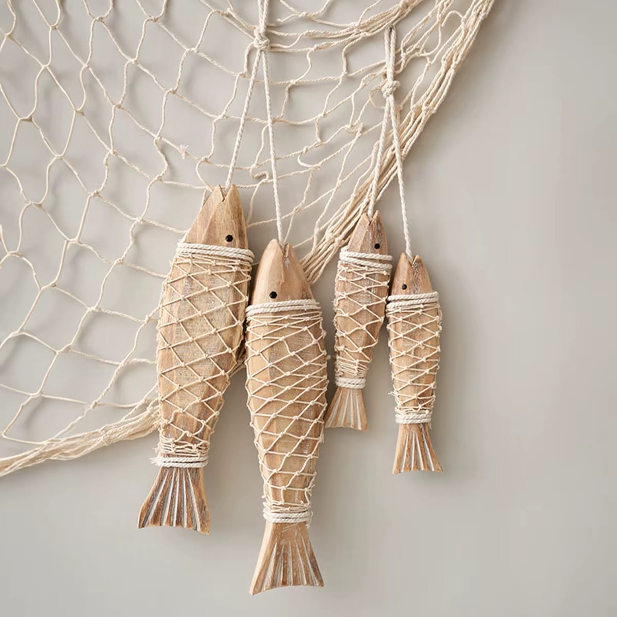 Carved wood fish wrapped in natural rope hanging on a wall