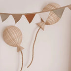 Two hand woven rattan balloons with trailing strings hanging on a wall