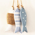 Three painted wood fish hanging together on a twine cord