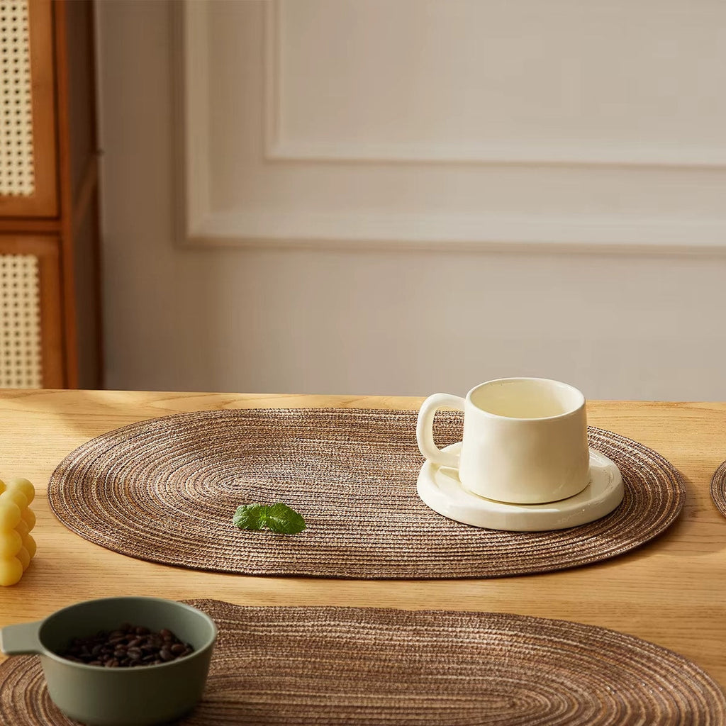 Four oval placemats with a woven straw look in natural tones