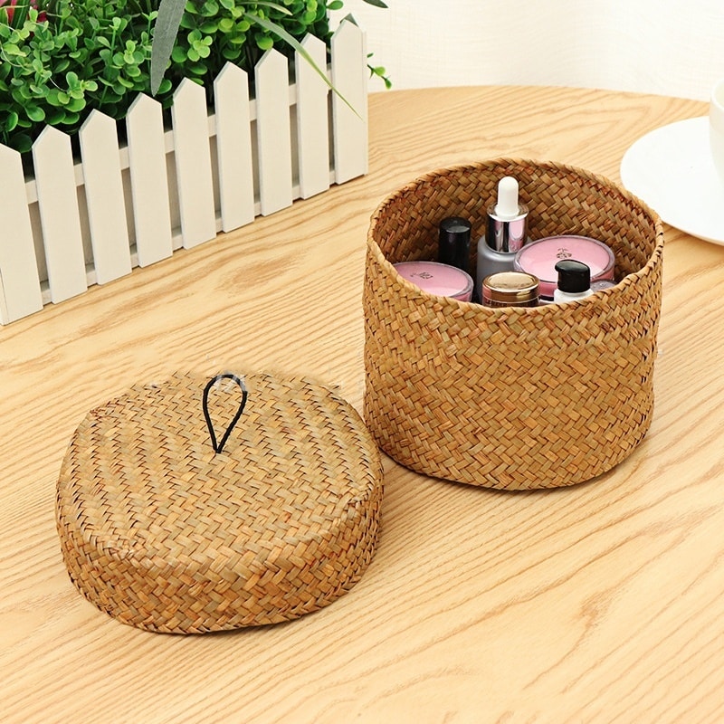 Small round woven straw basket with lid holding cosmetics