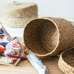 Small round woven straw basket with lid holding cosmetics