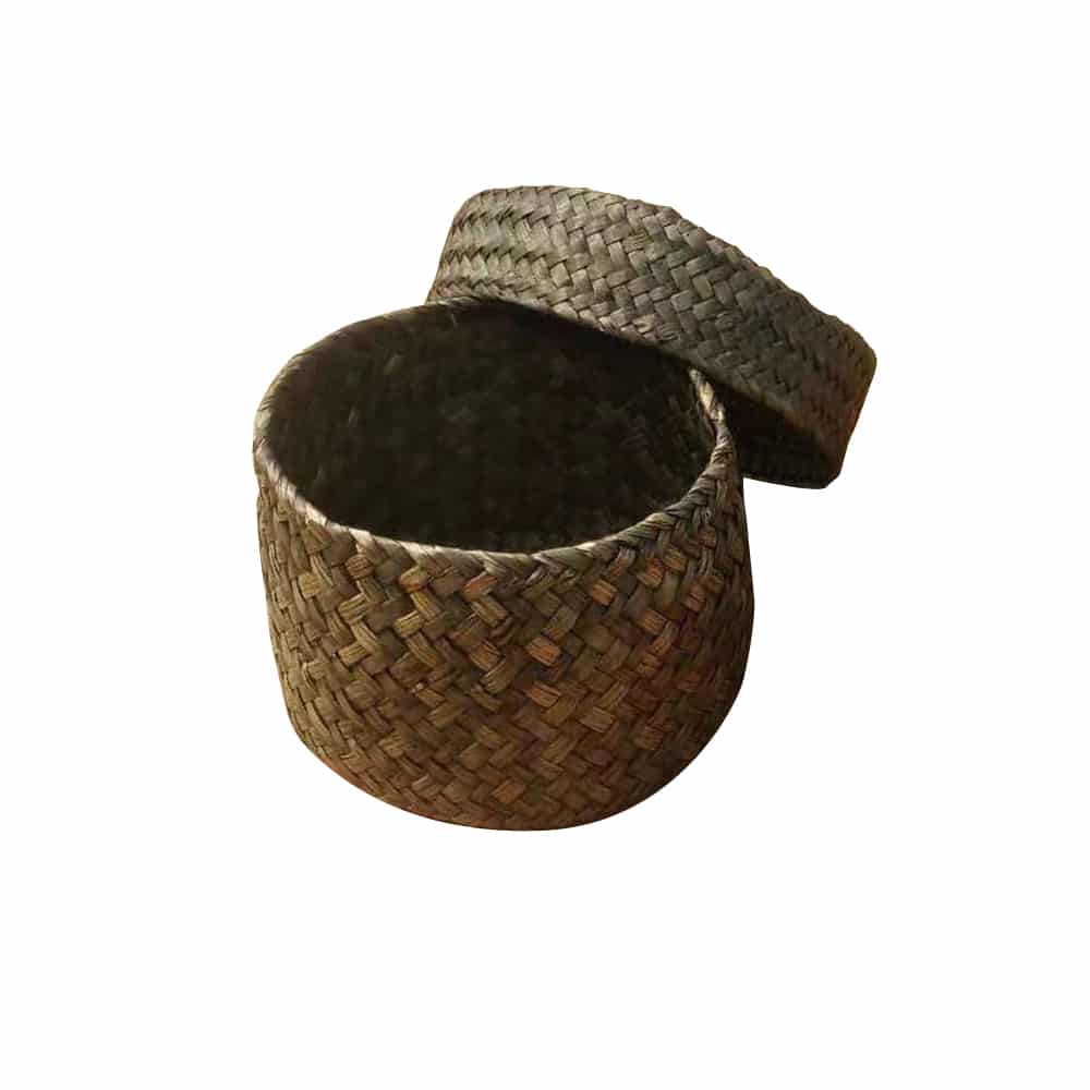 Small round woven straw basket with lid holding cosmetics